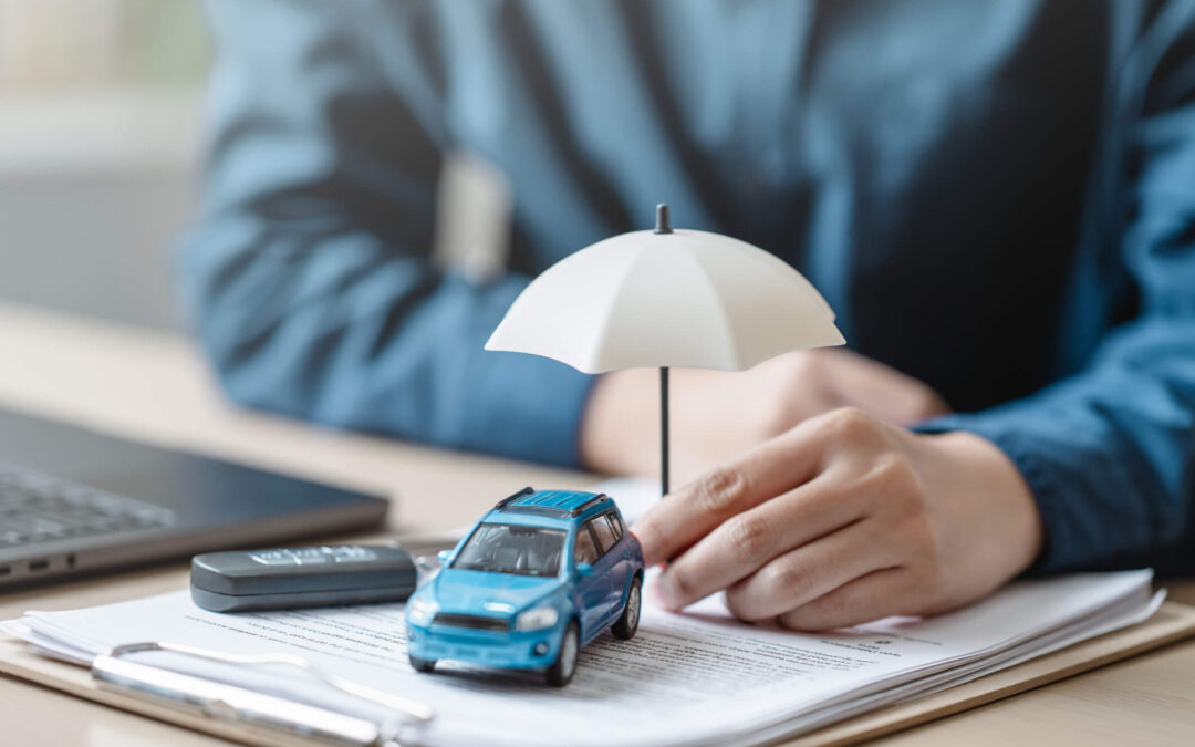 Car warranty and insurance concept; a person holding a mini umbrella under a toy car.
